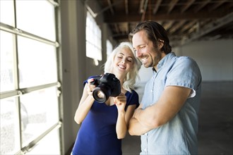 Woman and man looking at pictures in digital camera