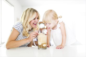 Mother drinking milkshake with daughter (2-3)