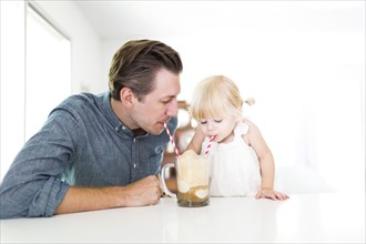 Father drinking milkshake with daughter (2-3)