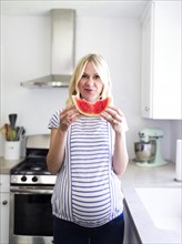 Pregnant woman holding slice of watermelon