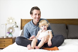 Portrait of father with daughter (2-3) in bedroom