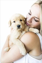 Studio shot of woman holding Golden Retriever puppy in arms