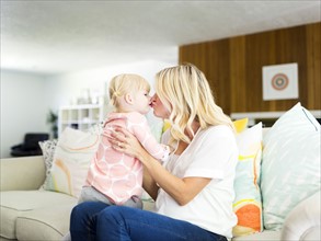 Woman kissing daughter (2-3) in living room