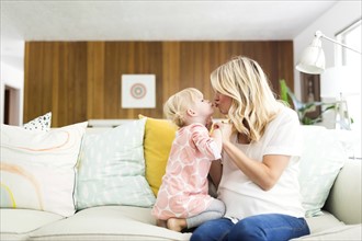 Woman kissing daughter (2-3) in living room