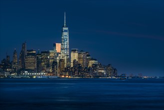Illuminated cityscape reflecting in river. New York City, New York, USA.