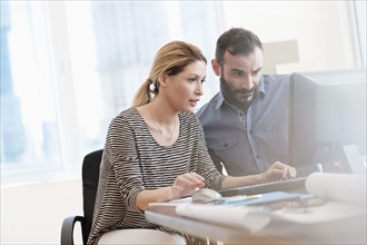 Man and woman looking at computer in office.