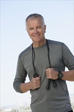 Portrait of man in sports clothing with jump rope.