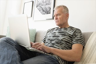Man sitting on sofa using laptop.