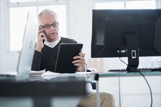 Man in office using smartphone and tablet.