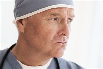 Portrait of surgeon in scrubs and surgical cap.