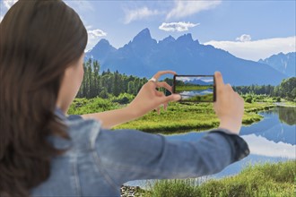 Young woman photographing mountain range. Grand Tetons, Grand Teton National Park, Wyoming, .