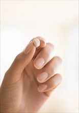 Hand holding vitamin pill.
