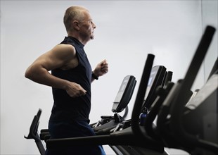 Man exercising in health club using treadmill.