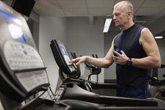 Man in health club adjusting treadmill before training.
