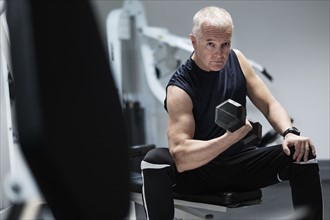 Man exercising with dumbbells on weight bench.