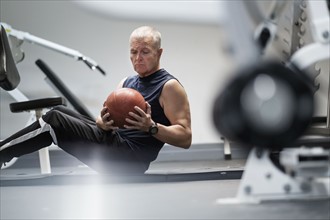 Man in health club exercising with ball.