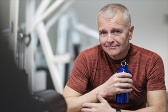 Portrait of man in health club with water bottle.