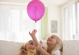Boy (4-5) and girl (6-7) playing with pink balloon