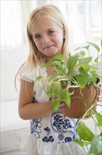 Girl (6-7) holding flower in flower pot