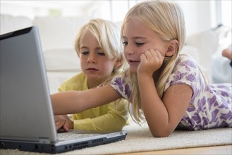Boy (4-5) and girl (6-7) using laptop