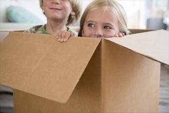 Boy (4-5) and girl (6-7) sitting in box