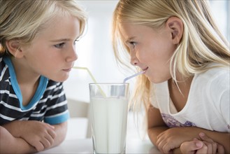 Brother (4-5) with sister (6-7) drinking milk from glass