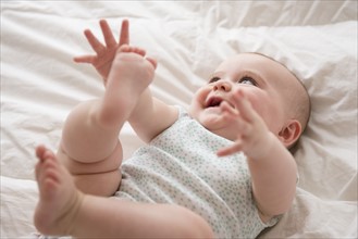 Baby girl (12-17 months) lying down with arms and legs up