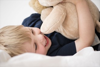 Smiling boy (2-3) with toy lying down on bed