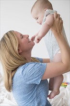 Mother lifting baby daughter (12-17 months)