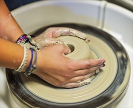 Woman shaping clay bowl on pottery wheel
