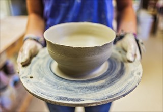 female potter holding clay bowl