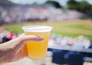Close-up of hand holding beer at stadium