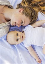 Mother lying down with baby boy (6-11 months)