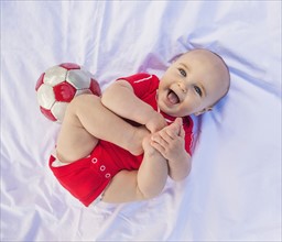 Portrait of baby boy (6-11 months) lying down with soccer ball