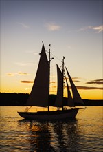 Silhouette of sailboat against sunset sky
