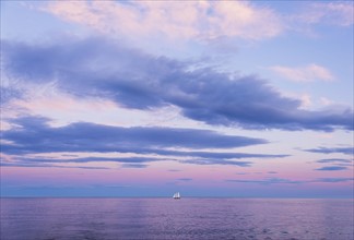 Pastel-colored sunset seascape with sailboat