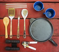Skillet, cups and cooking utensils on picnic table