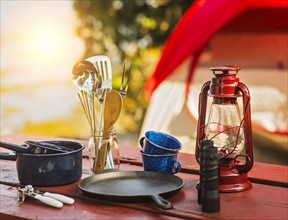 Oil lamp, binoculars and cooking utensils on picnic table