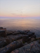 Rocky cliff by sea at sunrise