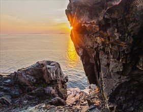 Rock formations by sea at sunrise