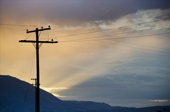 Silhouette of electricity pylon against cloudy sky
