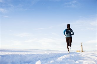 Rear view of mature woman running in snow