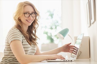 Portrait of young woman working on laptop at home.