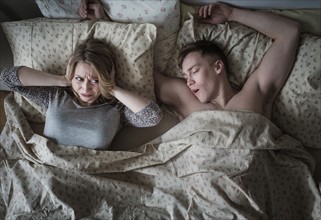 Young couple in bed, man snoring.