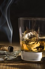 Whiskey and cigar on table.