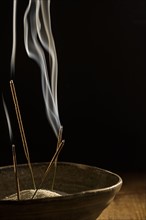 Incense in bowl on black background.