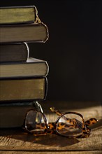 Eyeglasses and stack of books on table.