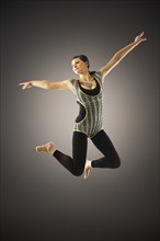 Young woman jumping on black background.