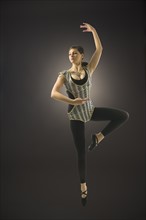 Young woman dancing against black background.