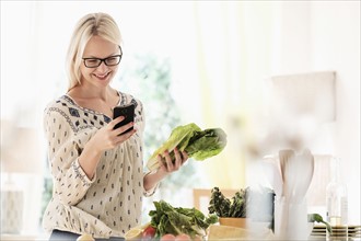 Woman preparing food and using phone.